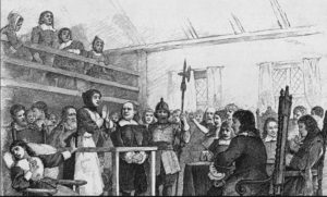 A¬†woman in handcuff on trial for witchcraft.