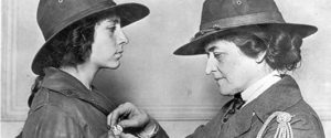 Juliette Gordon Low, founder of Girl Scouts, pinning a badge on a scout.