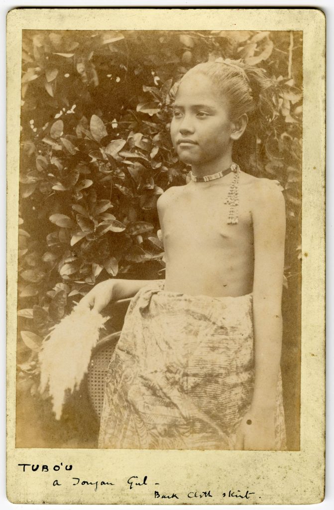 A young girl, Tubo'u, standing among trees in native dress