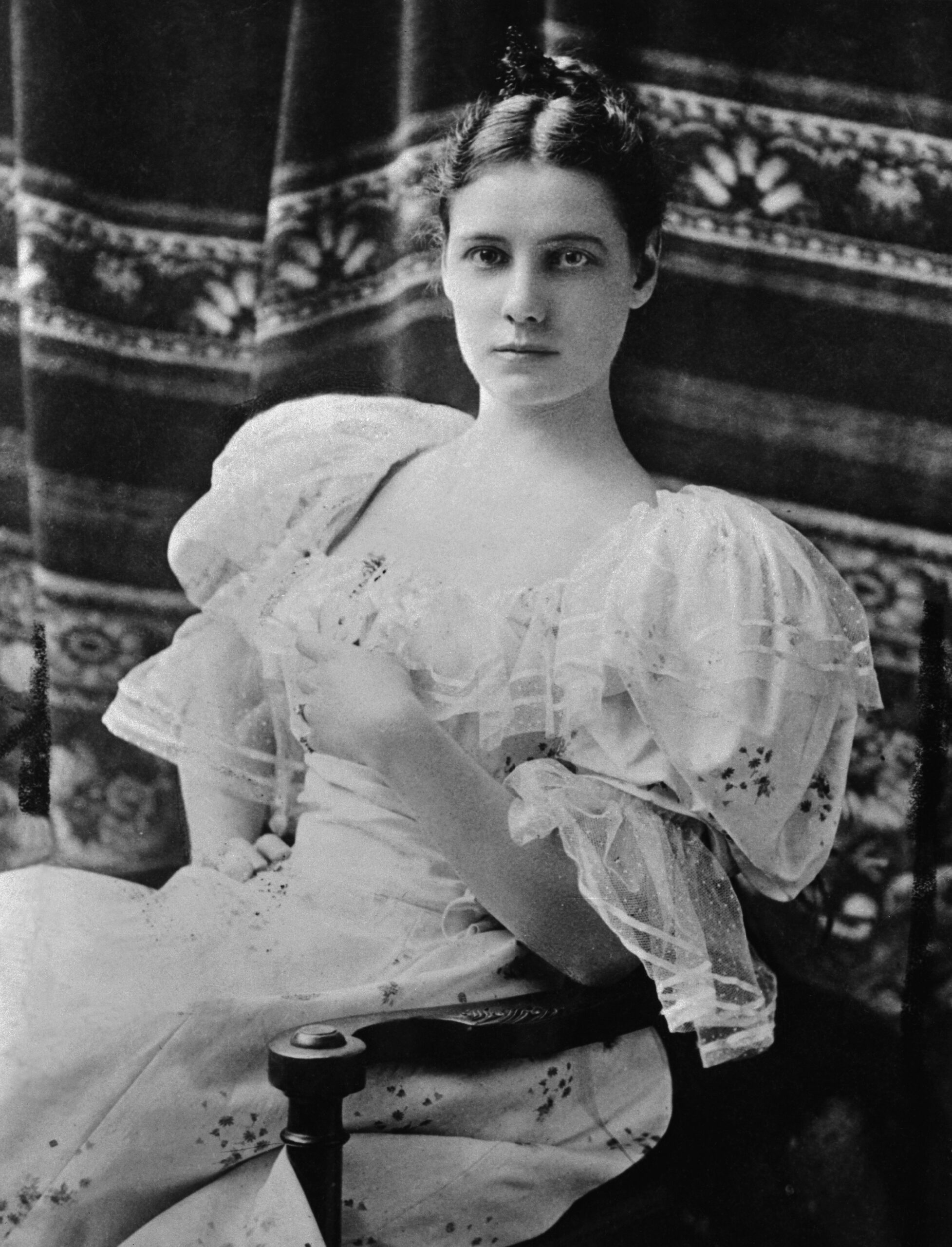 Seated young white woman in a white gown with puffy sleeves