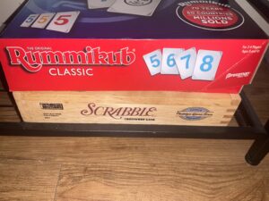 Rummikub and Scrabble boxes on a  table.